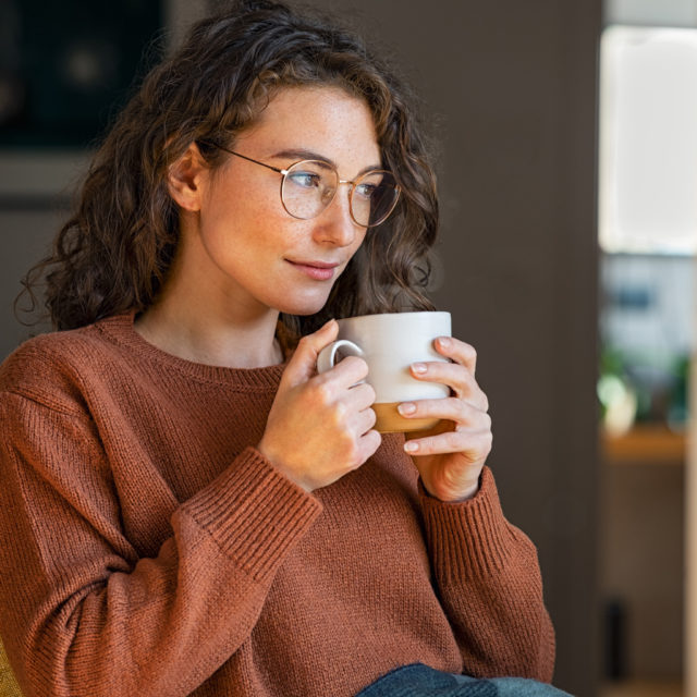 Young woman drinking tea at home during winter